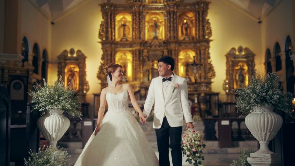 Basi and Erika holding hands before a golden church altar